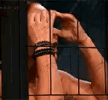a man is behind a fence covering his face with his hands