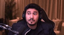 a man wearing headphones is sitting in front of a microphone making a funny face .
