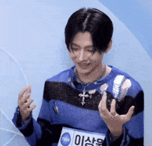 a man wearing a blue and black striped sweater has a name tag that says ' 이상우 '