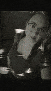 a woman wearing glasses takes a selfie in a black and white photo .