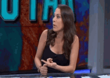 a woman in a black tank top is sitting at a desk in front of a wall that says utah