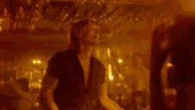 a man is playing a guitar in a dark room and talking to a woman .