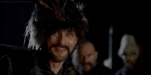 a man with a beard and mustache is holding a sword in his right hand