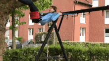 a person swinging on a swing set in front of a red building