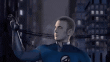 a man in a fantastic four costume is standing in front of a city at night .