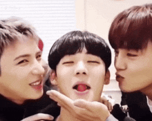 a group of young men are making funny faces and one of them is licking another man 's face .