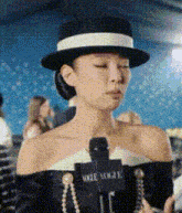 a woman wearing a black hat is talking into a vogue microphone