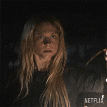 a woman with long blonde hair is holding a lantern in her hand in the dark .