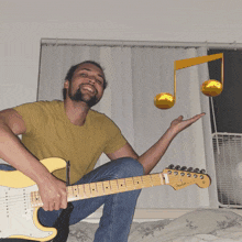 a man is holding a yellow fender guitar in his lap