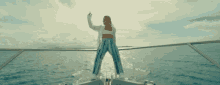 a woman is standing on the back of a boat in the water