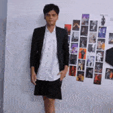 a young man stands in front of a wall with pictures on it including one that says ' i 'm a boy '