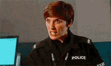 a woman in a police uniform is making a funny face while standing in front of a computer .