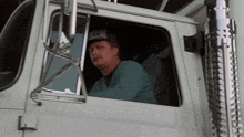 a man is sitting in the driver 's seat of a white truck .