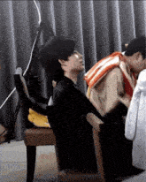 a man is sitting in a chair next to another man with a life jacket on his back .