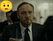 a man in a suit and tie is holding a cup of coffee