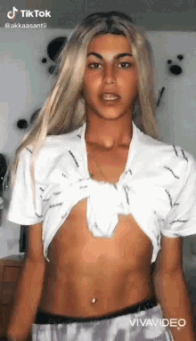 a woman with long blonde hair is wearing a crop top and purple shorts .