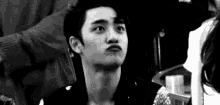 a black and white photo of a young man making a face .