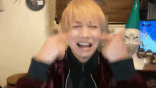 a man with blonde hair is making a funny face with his hands