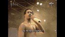 a shirtless man is singing into a microphone and the words va te faire foutre are displayed below him