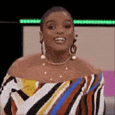 a woman wearing a striped top and earrings is smiling .
