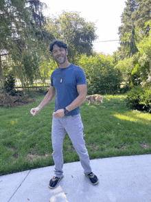 a man in a blue shirt stands on a sidewalk in front of a dog