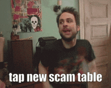 a man says tap new scam table in front of a painting of a skull