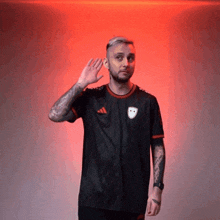 a man wearing a black adidas shirt waves his hand