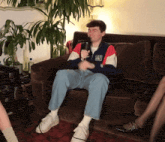 a man wearing a new york giants jacket is sitting on a couch with a microphone in his hand