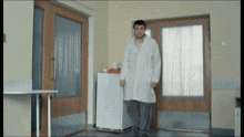 a man in a lab coat is standing next to a refrigerator