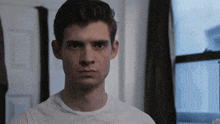 a man in a white t-shirt looks at the camera