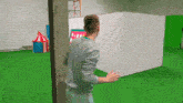 a man is standing in front of a green screen holding a piece of paper that says ' a ' on it