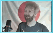 a man with a beard singing into a microphone in front of a japanese flag