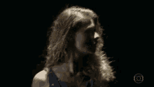 a woman with curly hair is dancing in a dark room with her hands in the air .