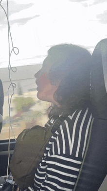 a woman in a striped shirt is sitting in a car