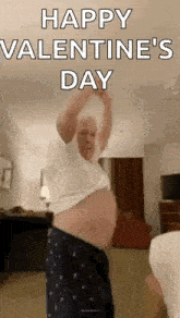 a man is dancing in a living room with his arms in the air and says happy valentine 's day .