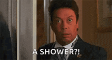 a man in a suit and tie is standing in front of a door and asking for a shower .