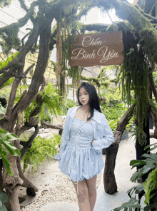 a girl in a blue dress stands in front of a sign that says chon bình yen