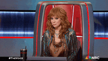 a woman is sitting in a chair with a nbc logo on the bottom