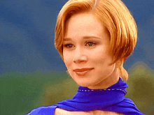a woman with red hair is wearing a blue top