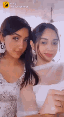 two women are posing for a picture together and one of them is wearing hoop earrings .