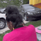 a woman in a pink shirt is sitting in front of a gm car