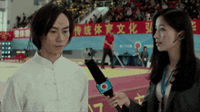 a man is being interviewed by a woman in front of a sign that says ' chinese ' on it