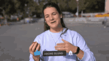 a woman in a blue sweater is holding a sign that says ' abone olund ' on it