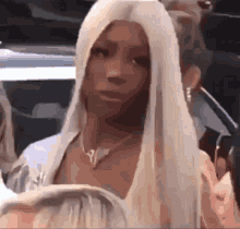 a woman with long white hair is sitting in a car with other people .