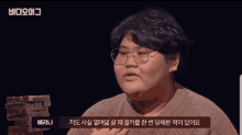 a man with glasses and a stack of jenga blocks behind him