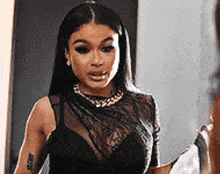 a woman is standing in front of a mirror wearing a black lace top and a gold necklace .