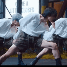 a group of people are dancing in front of a sign that says " one a little closer "