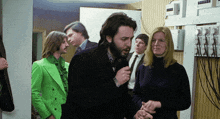 a man in a green jacket is talking to a woman in a black shirt