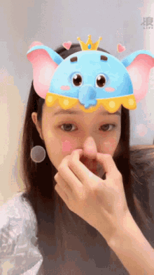 a woman wearing a blue elephant mask with a crown on her head