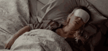 a woman is sleeping in a bed with an eye mask on her eyes .